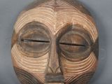 une image représentant un masque en bois sur lequel figure un visage