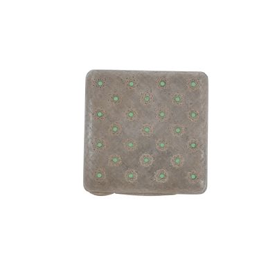 a small square tile with green flowers on it