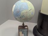 a small globe on a stand next to a small clock