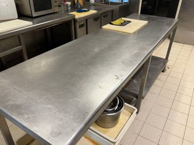 plan de travail en acier inoxydable dans une cuisine commerciale avec des casseroles et des poêles dessus
