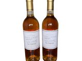 two bottles of wine sitting next to each other on a white surface