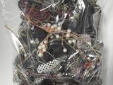 un sac contenant un assortiment de bijoux posé sur une surface blanche