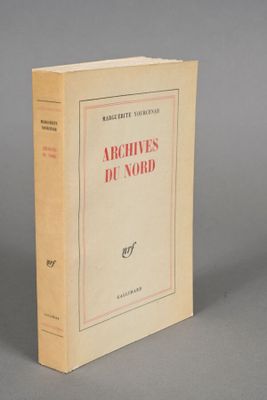 an old book sitting on top of a table next to a gray wall