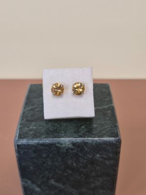 une paire de boucles d'oreilles en or posée sur un carré blanc
