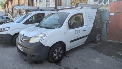 plusieurs fourgonnettes blanches garées sur un parking à côté d'un immeuble