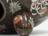 a black vase with a flower design on it