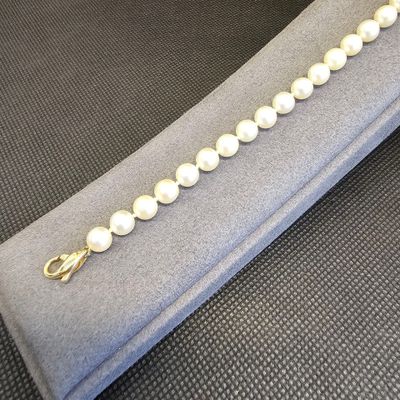 bracelet en perles avec un fermoir en or, présenté dans un étui en velours gris