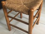 a wooden chair with a woven seat on a tile floor
