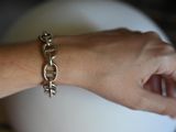 a woman ' s hand holding a silver bracelet with a chain