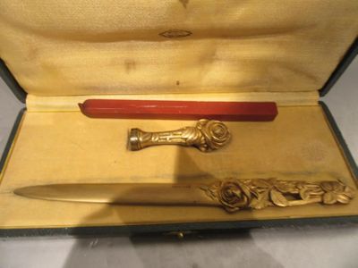 un stylo rouge et un couteau doré dans un étui