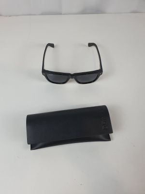une paire de lunettes de soleil noires et un étui noir posés sur une surface blanche