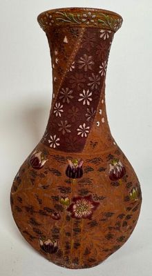 un vase marron orné de fleurs, posé sur un fond blanc