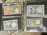 several different types of currency are displayed in a binder on a table