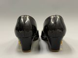 the back view of a pair of black heels with gold accents