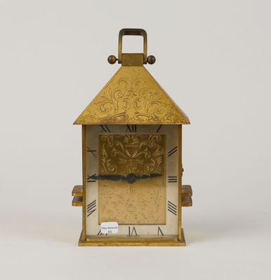 une petite horloge en or avec des chiffres romains