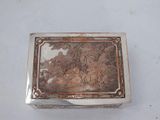 an antique silver box with a painting on it on a white surface
