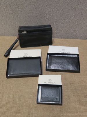 trois portefeuilles en cuir noir et un sac à main noir posés sur une table