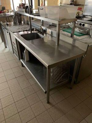 de nombreuses tables en acier inoxydable dans une cuisine équipée d'un évier