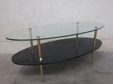 a glass coffee table with gold legs and a glass top