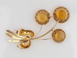 gold plated flower brooch with yellow stones on a white background