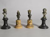 quatre pièces d'échecs en bronze et en marbre posées sur un fond blanc