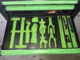 une boîte à outils verte posée par terre, contenant des outils
