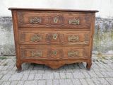 une commode en bois posée sur un sol pavé