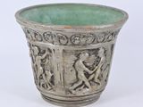 un vase argenté avec un socle vert sur fond blanc