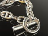 a close up of a chain bracelet with two rings on a black surface