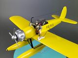 yellow model airplane with pilot sitting on the wing of the plane