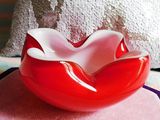 a red and white bowl sitting on top of a pink pillow