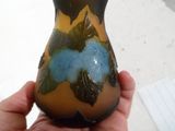 une main tenant un vase sur lequel se trouve une fleur bleue