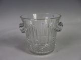 a glass ice bucket with a handle on a table