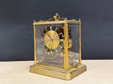 a gold clock sitting on top of a wooden table
