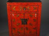 an old red cabinet with a black top and gold flowers on it
