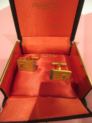 two gold cufflinks in a red box on a table