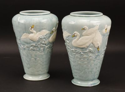 deux vases décorés de cygnes, posés sur une table