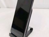a black cell phone on a stand on a white surface