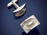 two silver cufflinks with a cross on them on a blue background
