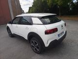 the rear end of a white car parked in a parking lot