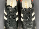 black and white sneakers with orange soles on a gray surface