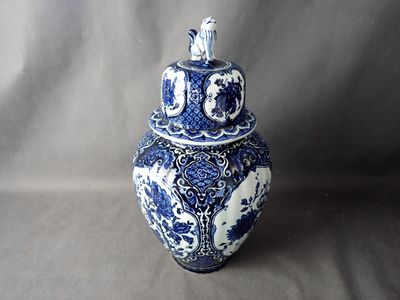 a blue and white vase with a lid sitting on a table