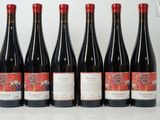 six bottles of red wine are lined up on a table