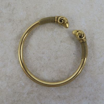 a close up of a gold bracelet with two skulls on it
