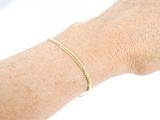 a woman ' s arm with a gold bracelet on it