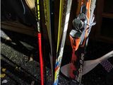 many skis and ski poles that are leaning up against the wall