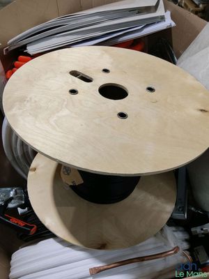 une bobine en bois posée dans une boîte remplie de fils