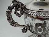 a silver teapot on a stand with a bird on it