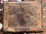 an image of a brown leather purse sitting on top of a colorful rug