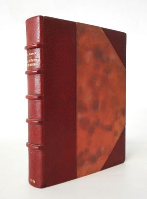 an old book with a red cover sitting on top of a white table